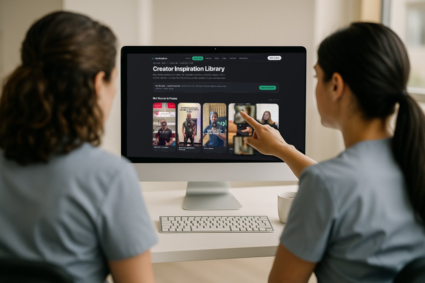 Two front-desk staff at a practice reviewing a training module together on a desktop screen